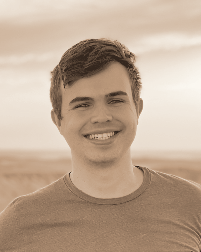 Davis Dunaway smiling outdoors at sunset, in warm monochrome.